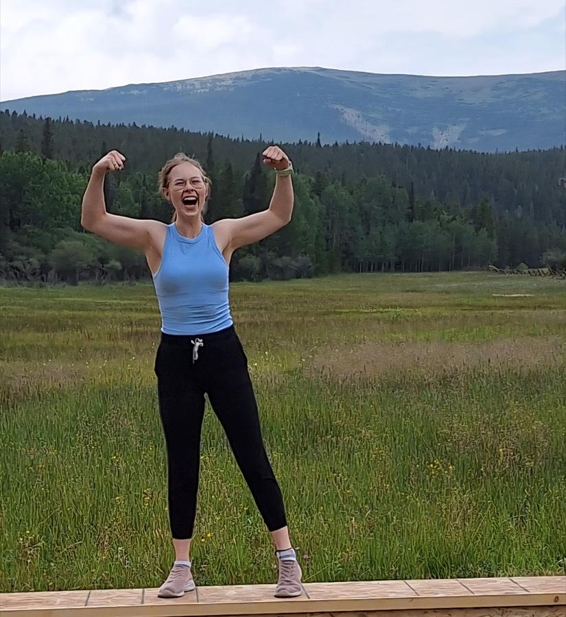 Chelsea, CoachLoop's founding coach, celebrating in front of a mountain meadow
